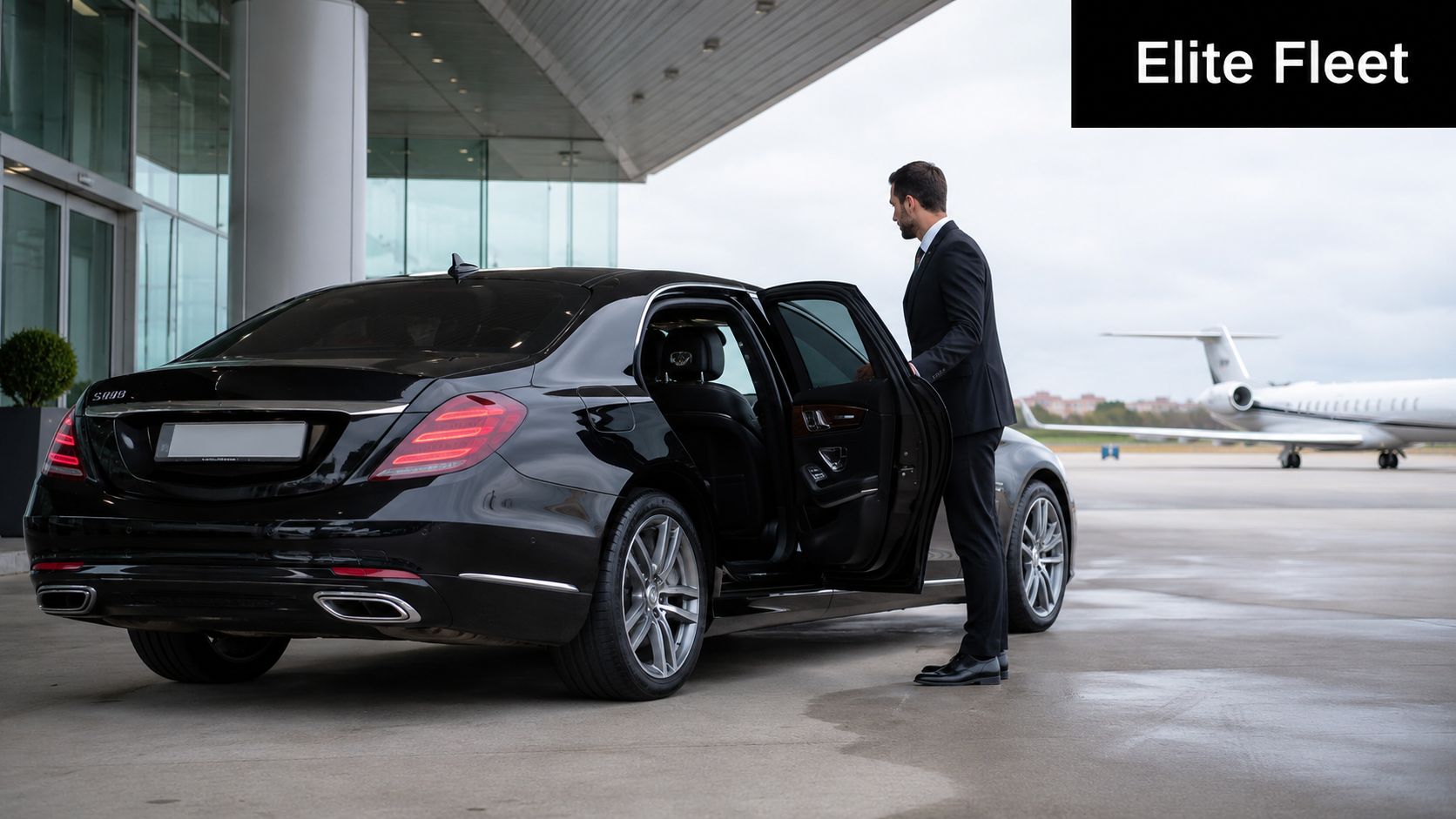 A professional chauffeur in a suit opens the door of a black luxury sedan at an airport.