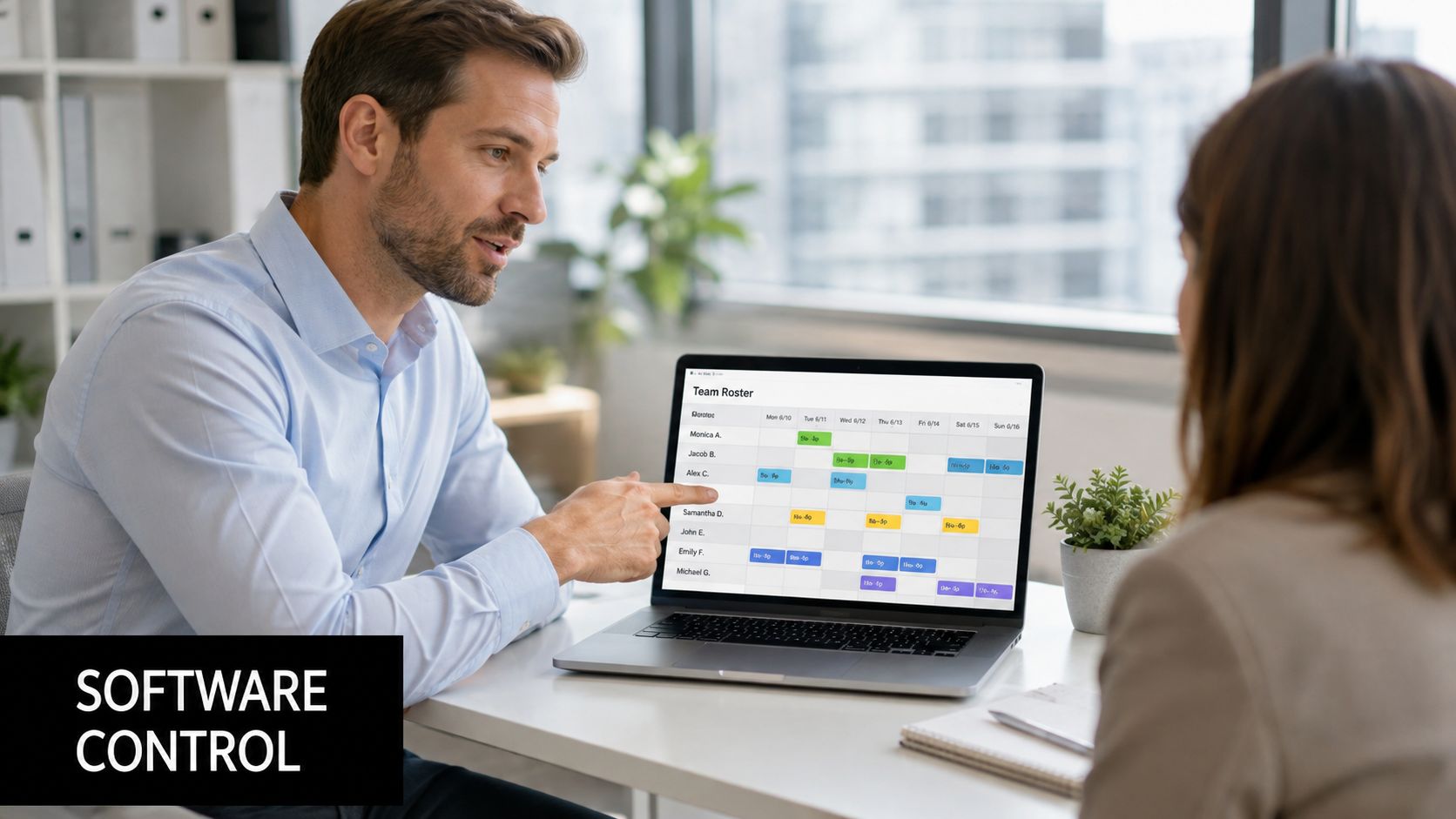 A professional man showing his colleague a digital team shift roster on a laptop in an office.
